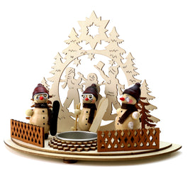 Holz Teelichthalter "Kinder mit Schneemann", Vordergrund: Zaun mit Teelichthalter und 3 grinsenden Schneemännern mit Mütze, teilweise Brille und Ski-/Snowboard
Hintergrund: zeigt Kinder, welche Schneemann bauen mit Tannen- und Sternendetails am Rand